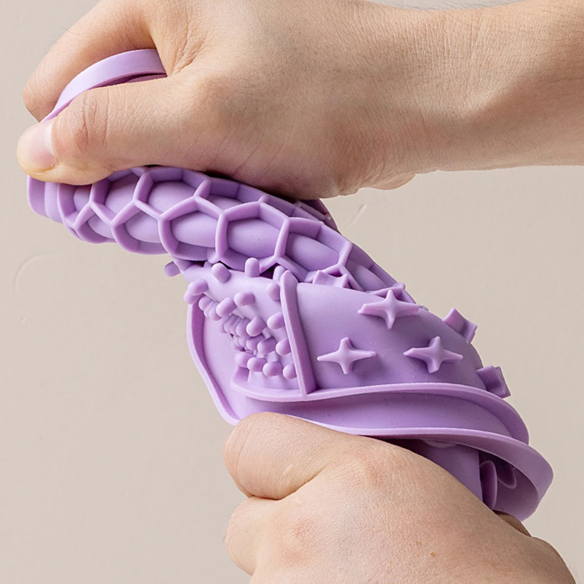 Hand bending a flexible purple silicone lick mat to show its soft texture | Pawnests